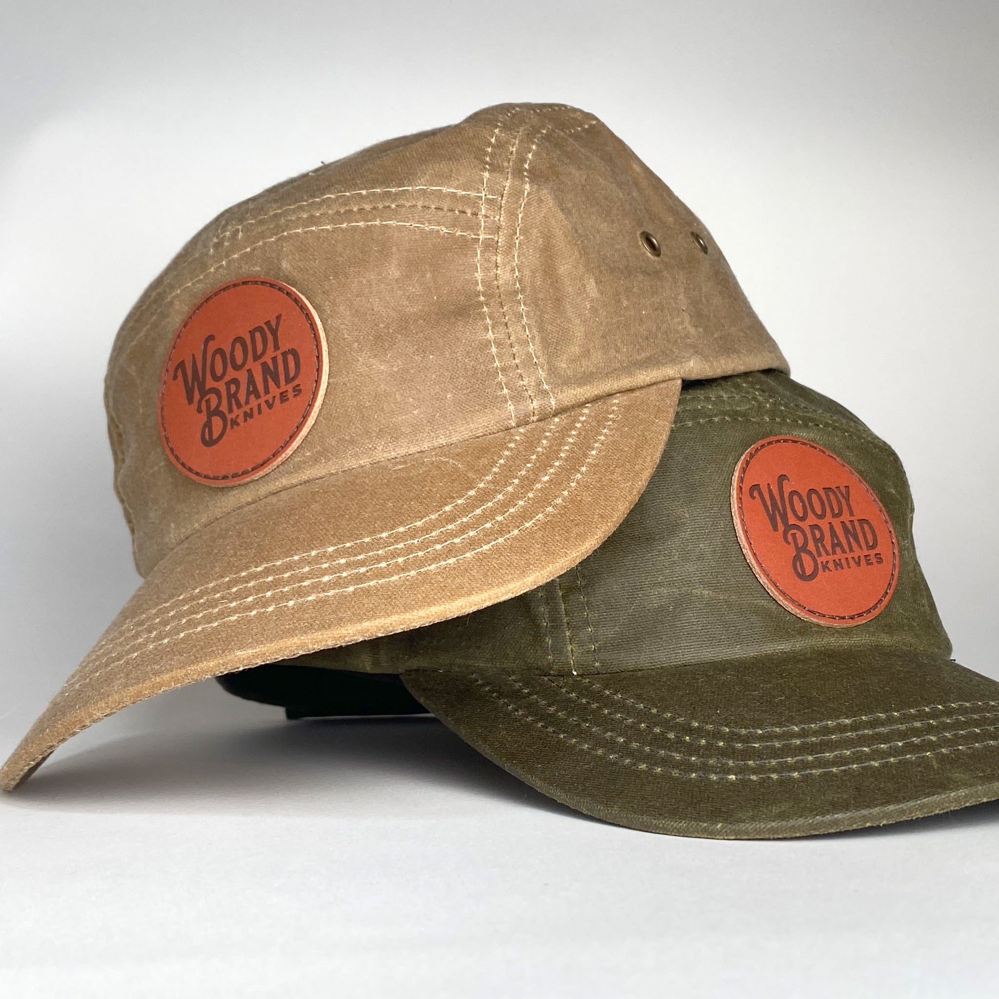 Two hats, one brown and one green, with 'Woody Brand' logos on a light gray background.